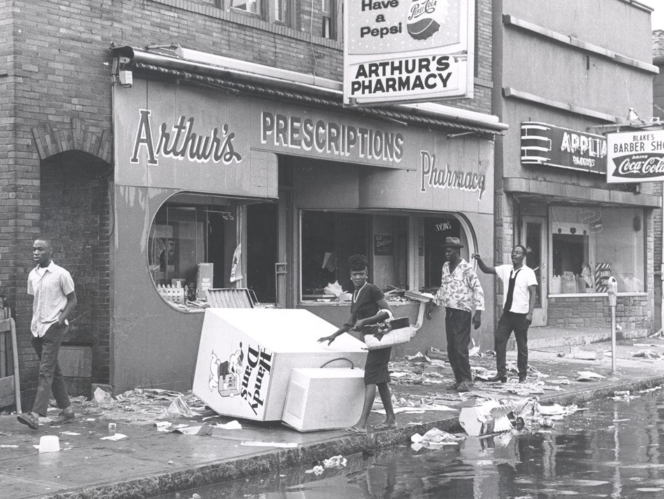 Citizens attempt to cross a debris-laden sidewalk on Joseph Avenue at Arthur's Pharmacy and Blake's Barber Shop. - PHOTO COURTESY THE CITY OF ROCHESTER, ROCHESTER, NEW YORK.