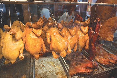 Poultry and pork hang in the meat counter at Asia Food Market. - PHOTO BY THOMAS DOOLEY