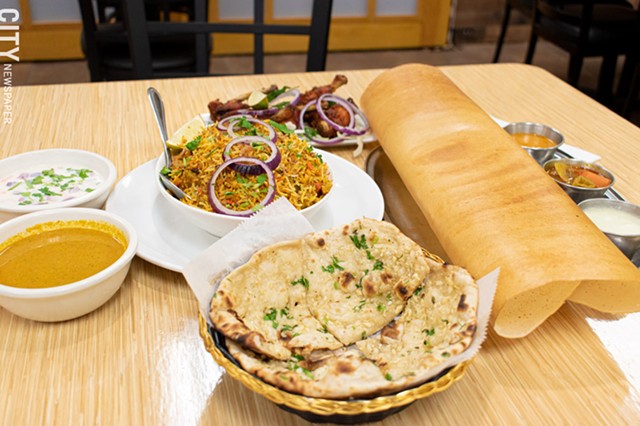Clockwise from front: garlic naan, vegetable biryani with yogurt raitha and sarlan (chili pepper and peanut gravy), chicken lollipops, and dosa with chutneys (coconut, sambhar, and tomato). - PHOTO BY JACOB WALSH