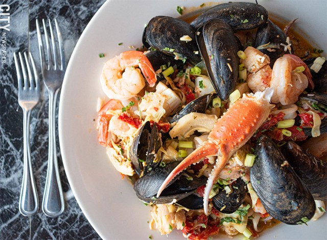 The Poseidon includes shrimp, scallops, lobster, crab, calamari, and mussels sautéed with sun dried tomatoes, roasted red peppers, and artichoke hearts in a lemon garlic sauce, over a bed of spinach rice. - PHOTO BY JACOB WALSH