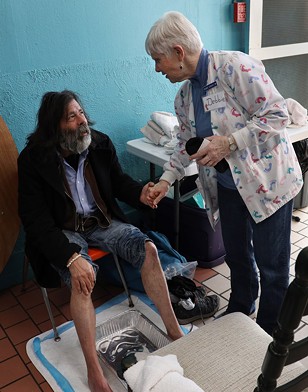 Debbie Sigrist, founder of the St. Joseph's House of Hospitality foot clinic, greets a guest. - PHOTO BY MAX SCHULTE