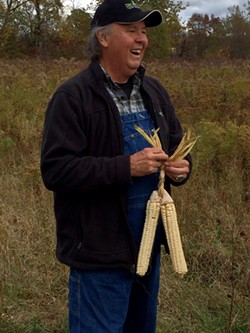 G. Peter Jemison, site manager at Ganondagan, braids together three ears of husked Iroquois White Corn. - PHOTO PROVIDED