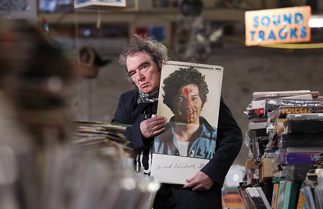 Armand Schaubroeck, co-owner of the House of Guitars and a former rock artist, displays the album he cut in 1968, "A Lot of People Would Like to See Armand Schaubroeck . . . DEAD." - PHOTO BY MAX SCHULTE