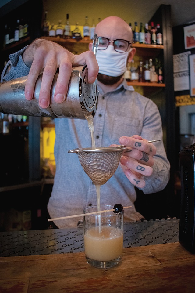 Cure's head bartender Donny Clutterbuck mixing up "Fashionably Late," which blends the flavors of orange, clove, molasses, and lemon juice. - PHOTO BY RYAN WILLIAMSON