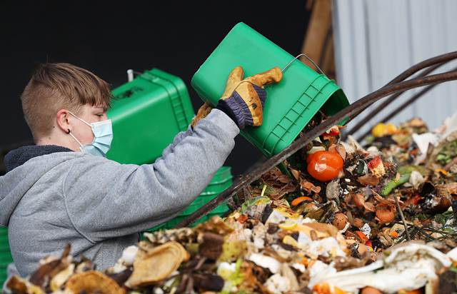 Beckett Putney empties household food scraps into a Dumpster at Impact Earth, a residential food scrap collector in Monroe County. - PHOTO BY MAX SCHULTE