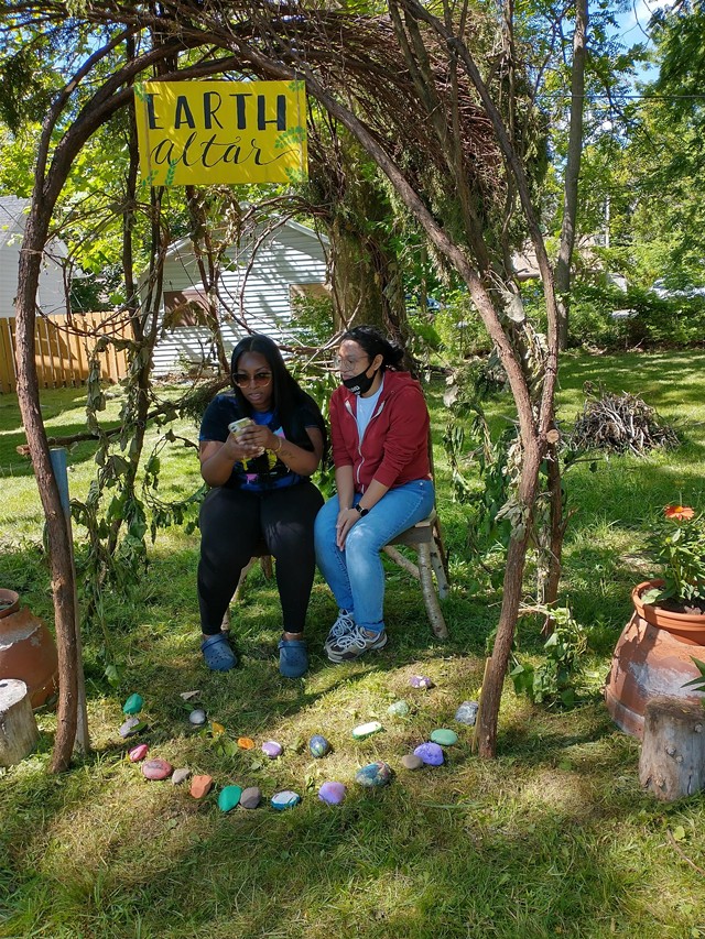 Youth educators Natasha Morrison and Alex Hubble sit at the Earth Altar they created outside of the Gandhi Institute in Rochester. - PHOTO PROVIDED