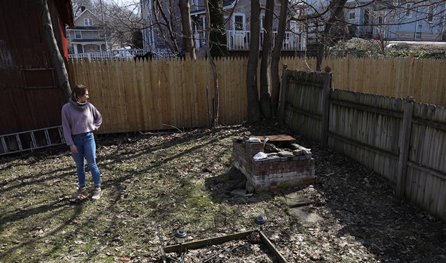 Alison Livada stands atop what used to be an underground fallout shelter in her backyard. The cavity has been filled in. Her home on Hartsen Street is one of nine in Rochester that still qualifies for a fallout shelter tax abatement. - PHOTO BY MAX SCHULTE