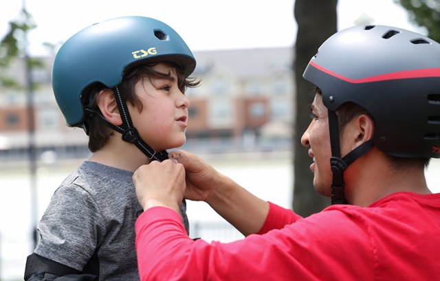 Rahmatullah has his helmet adjusted by Skateistan instructor Farzad Sharafi before the group's first trip to the ROC City Skatepark. - PHOTO BY MAX SCHULTE