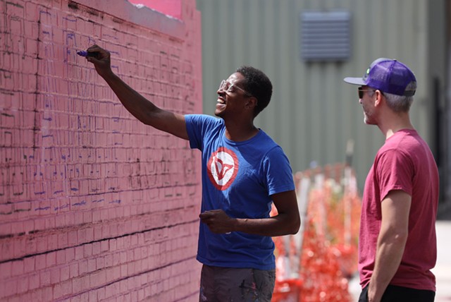 Shawn Dunwoody works on a mural on Scio Street while chatting with Bleu Cease, executive director of the Rochester Contemporary Art Center. Dunwoody is the lone artist advising the effort to create a downtown BID. Cease is a leading critic of the plan. - PHOTO BY MAX SCHULTE