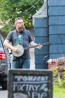 Jacob Rakovan strums the banjo outside of the July 11 Poetry & Pie Night. - PHOTO BY JOHN SCHLIA