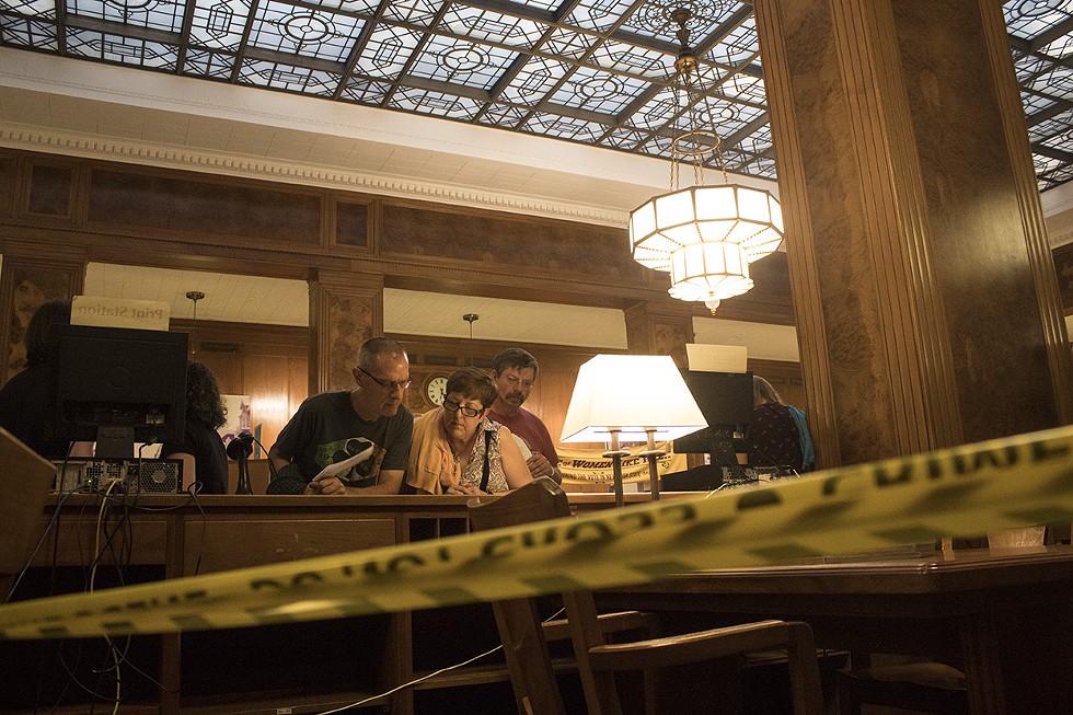 People examine clues during the Murder Mystery at the Central Library. - PHOTO BY ASHLEIGH DESKINS