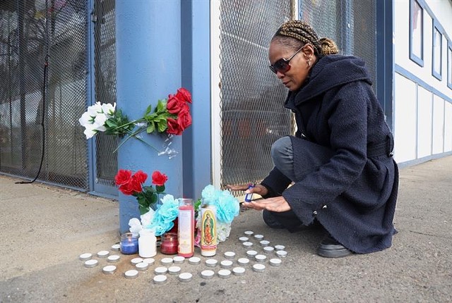 Lakeisha Commings, a customer of the Lake Avenue Mini Market, lights a candle at a memorial remembering clerk Anthony (Tony) Lovett, who was stabbed to death in the store Nov. 29, 2021.