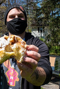 Jon Olek of Black Cat Baking Co., seen here with a cinnamon roll, works from his basement commercial-grade kitchen to supply several area cafes and shops with home-made pastries.