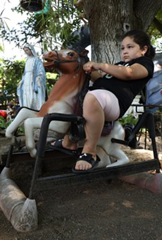 Zenobio and Carmen Rodriguez's granddaughter, Milani,  rides one of the few horses still attached to springs in their yard.